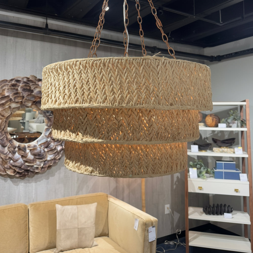 Woven pendant light hanging in a room with a sofa and decorative items.