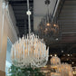 Chandeliers on display in a store with plants and furniture.