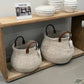 Woven baskets with wooden handles on a wooden shelf against a gray wall.