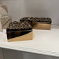 Two gold decorative boxes with textured lids on a white surface.