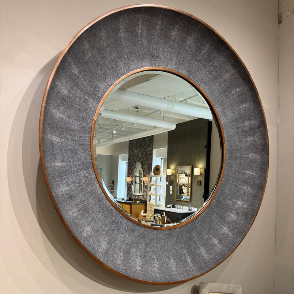 Round wall mirror with textured frame on a beige wall