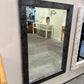 Rectangular mirror with a black frame on a light-colored wall.