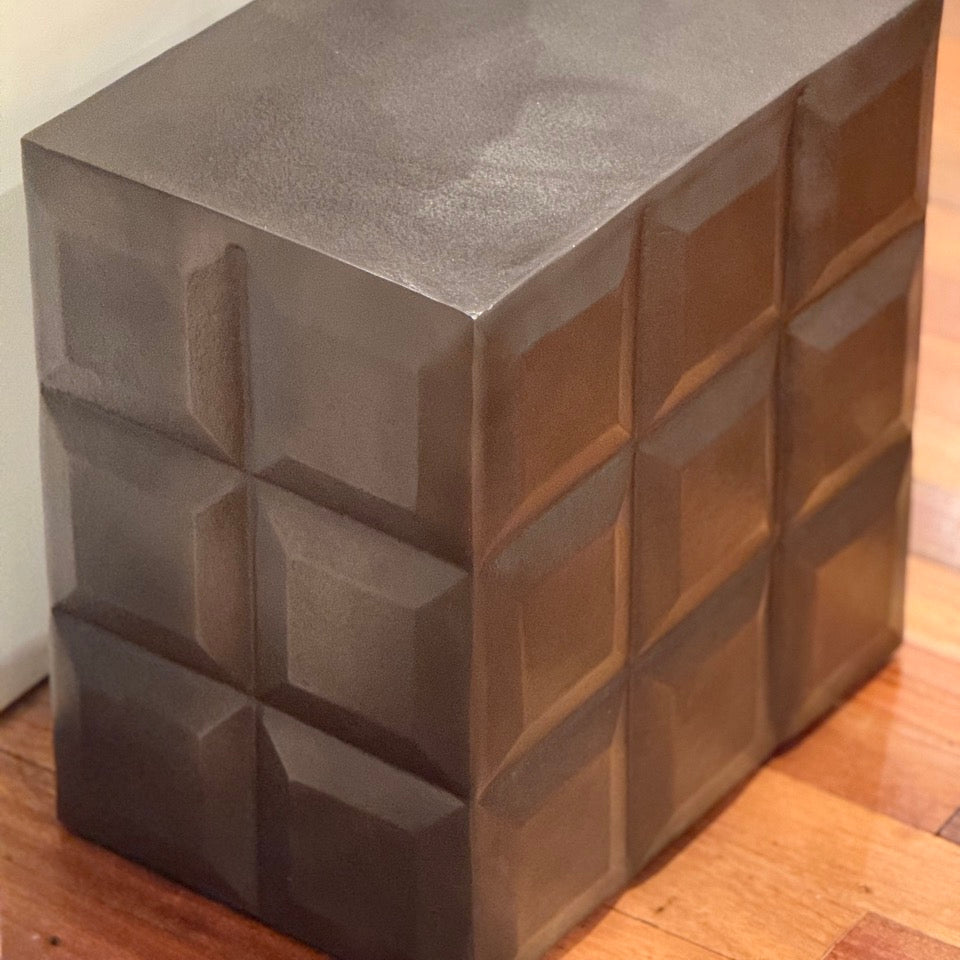 Rectangular concrete stool with a textured surface on a wooden floor.