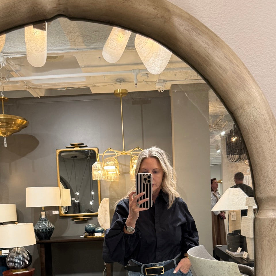 Person taking a mirror selfie in an interior design store with furniture and decor items.