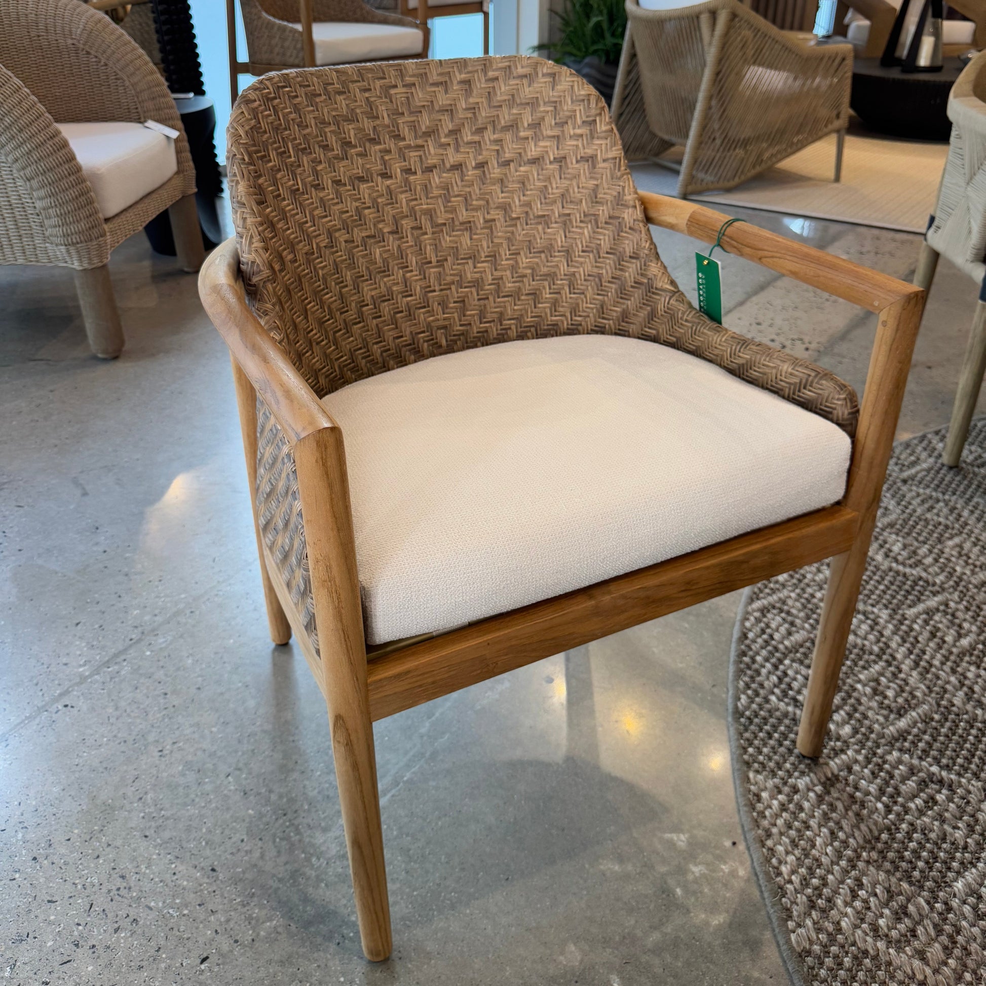 Chair with woven backrest and white cushion on a concrete floor.