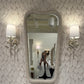 Person taking a mirror selfie in a room with decorative wall and lighting.
