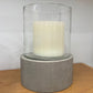 Cylindrical candle holder with a white candle on a wooden surface.