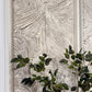 Decorative wall art with wavy pattern and green leaves in a white vase.