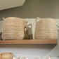 Two woven baskets on a wooden shelf against a neutral wall.