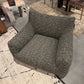 Gray textured armchair on a patterned rug with a dining area in the background