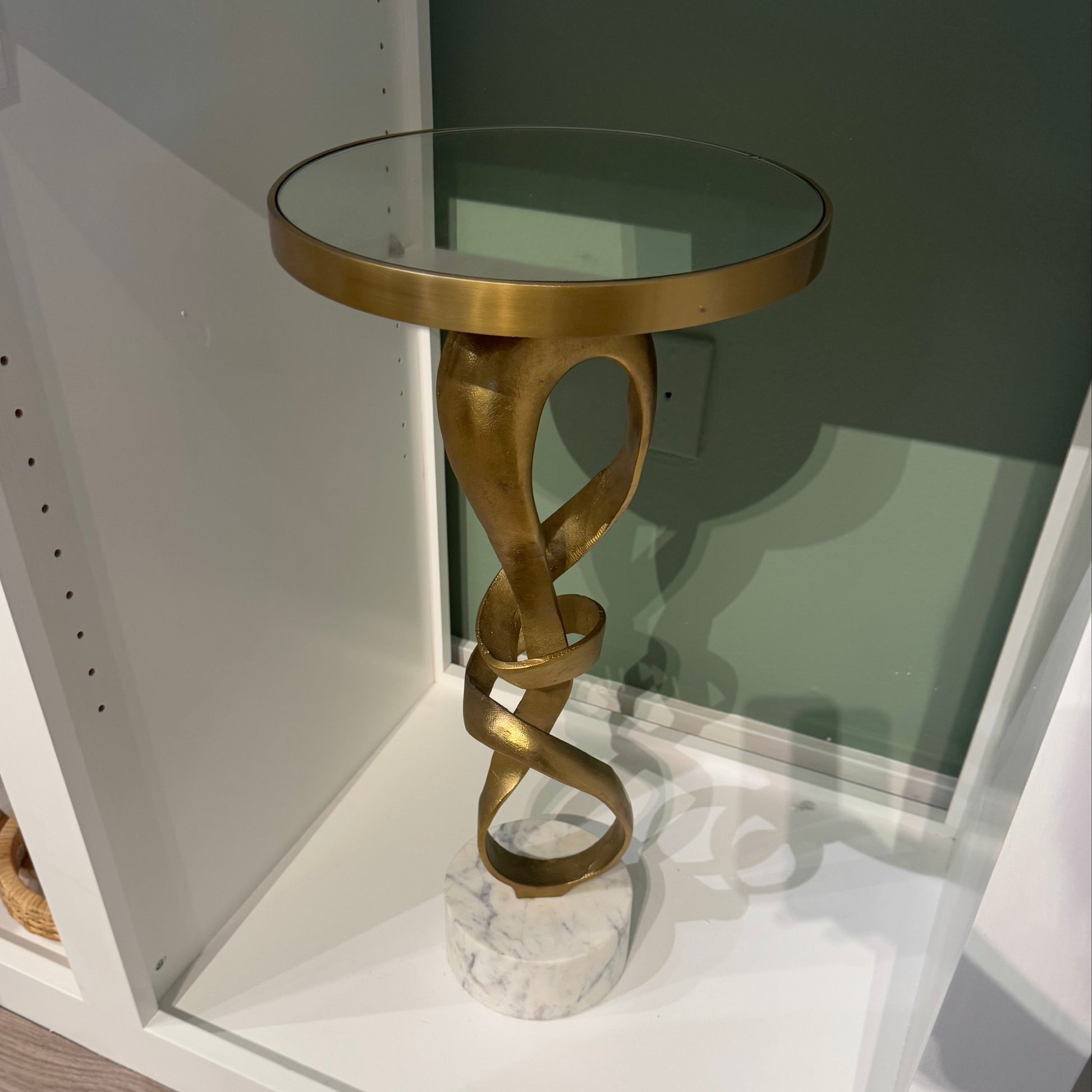 Gold decorative object on a white shelf with a wooden floor.