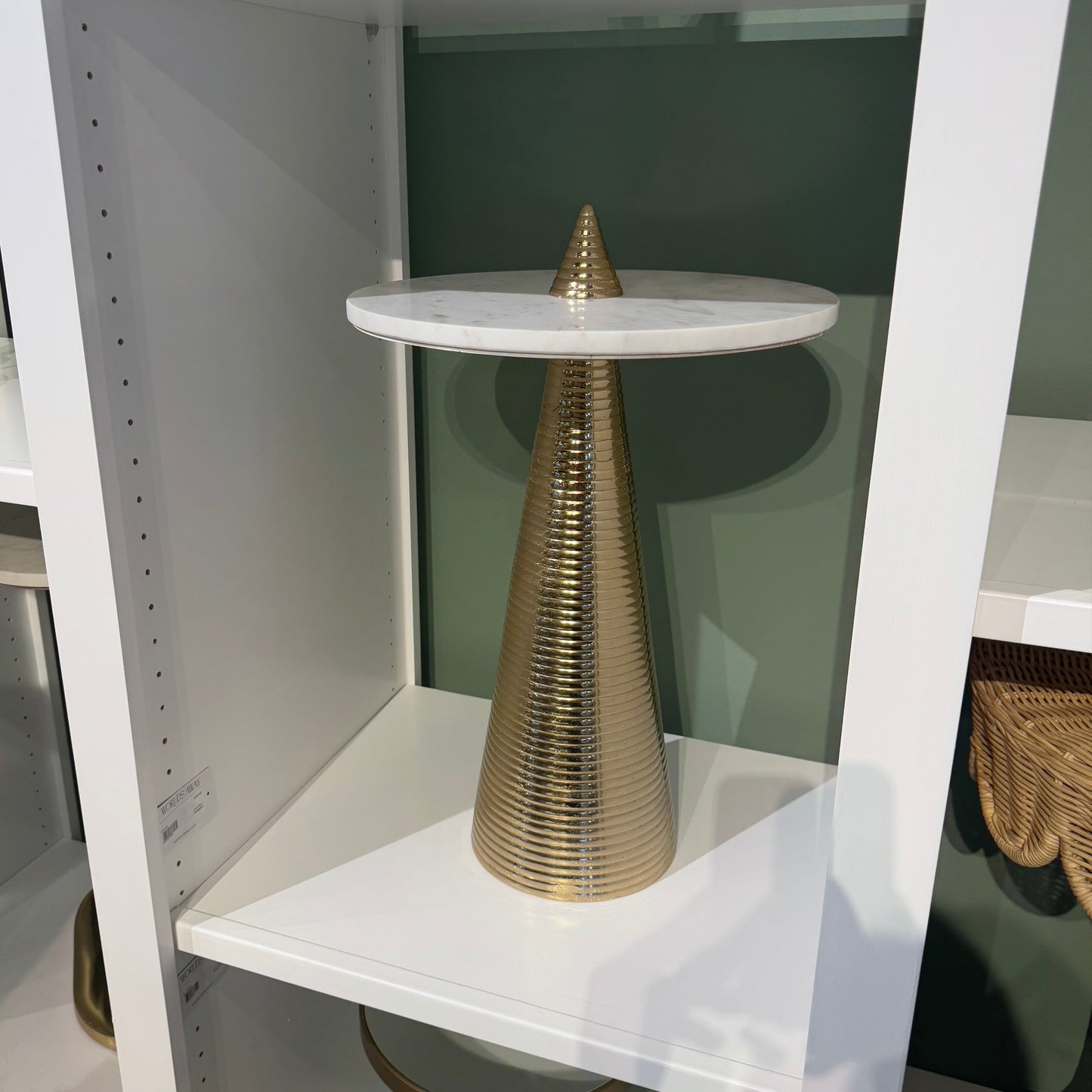 Decorative gold cone on a white shelf with a blurred background