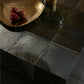 Dark stone countertop with a gold bowl containing red fruits