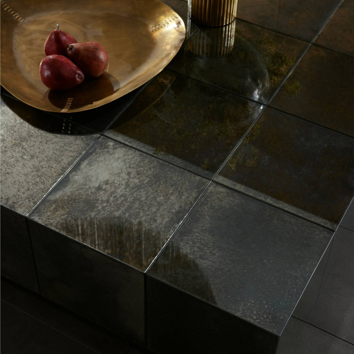 Dark stone countertop with a gold bowl containing red fruits