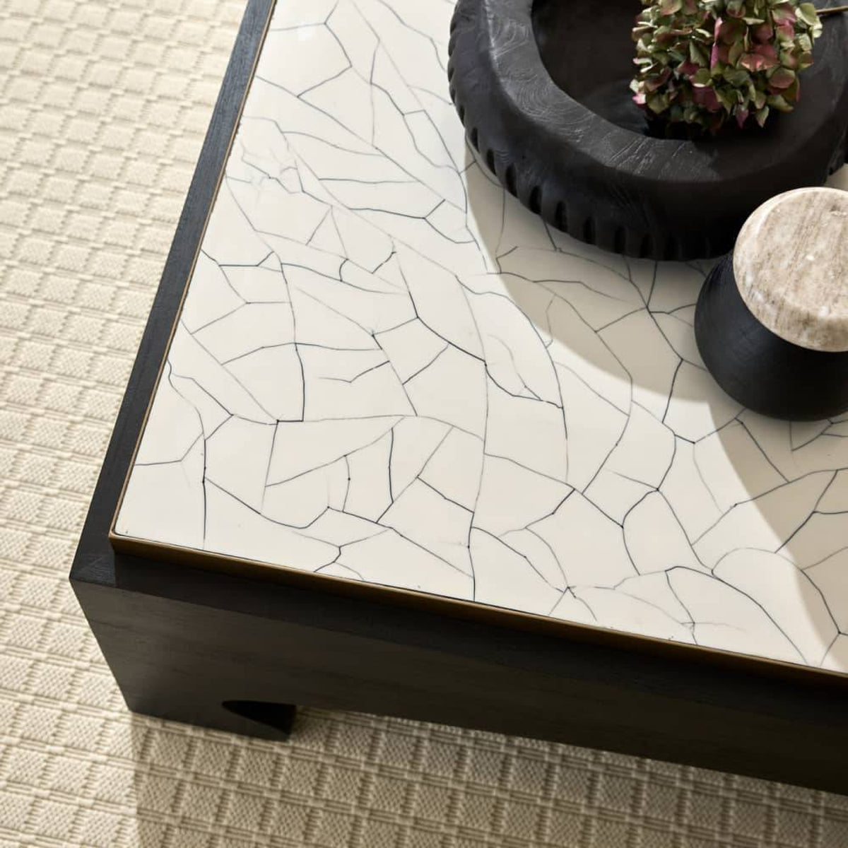 Decorative coffee table with a cracked white surface and black base on a textured floor.