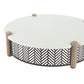Round outdoor coffee table with a white top, weathered wood posts, and a black geometric chevron lattice base.