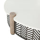 Round outdoor coffee table with a white top, weathered wood posts, and a black geometric chevron lattice base.