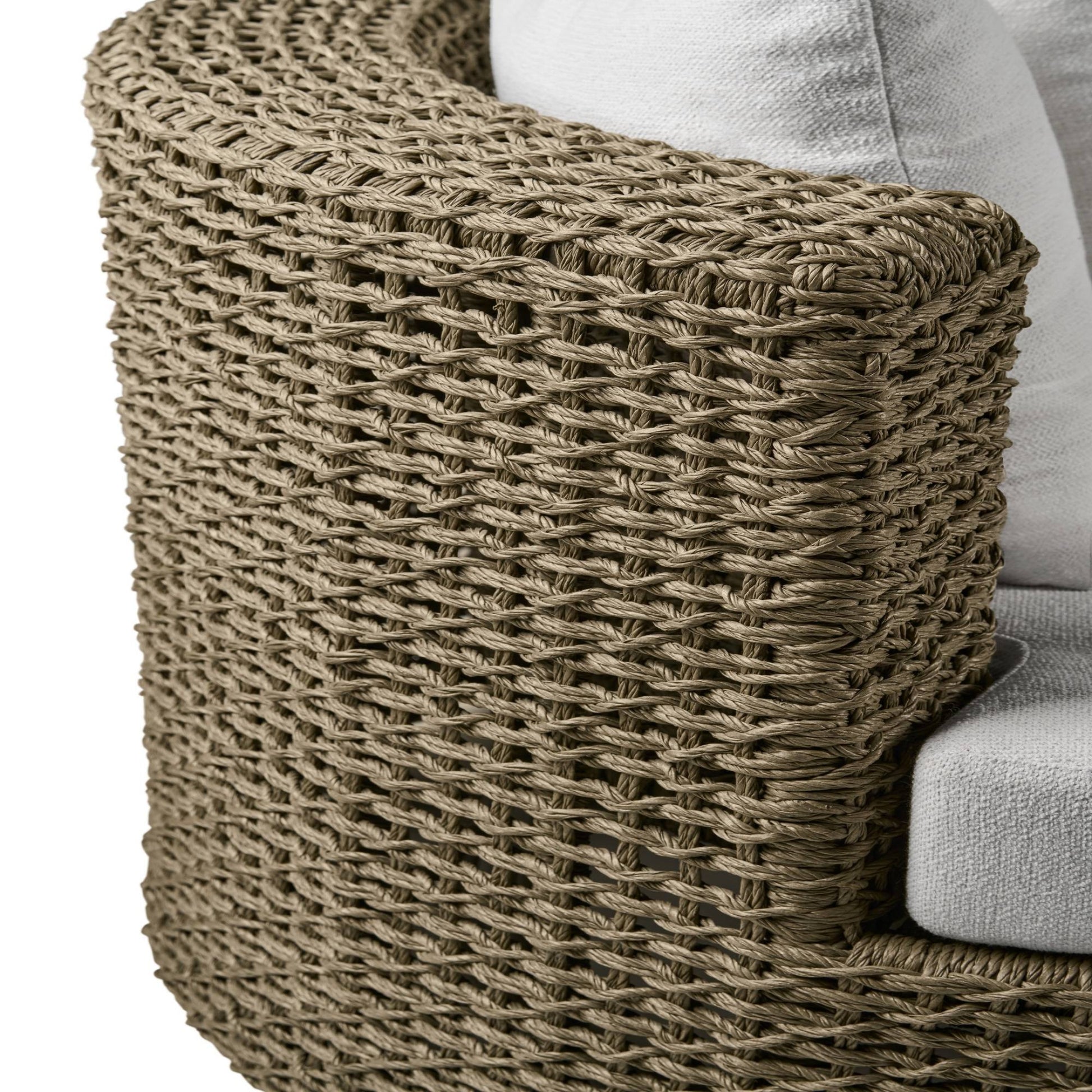 Close-up of a woven chair armrest with a white cushion.