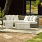 Outdoor patio set with wicker sofa and ottomans on a stone patio.