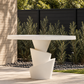 Sculptural ivory outdoor dining table with a textured edge and twisted pedestal base, styled with trailing greenery beside a sunlit swimming pool.