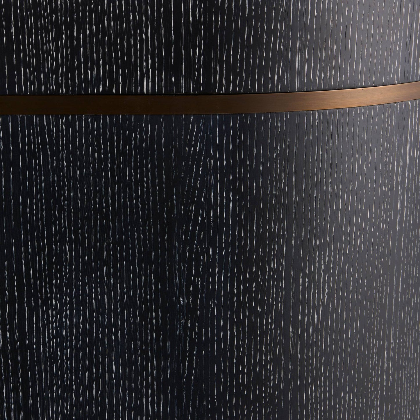Close-up of a dark charcoal textured surface with fine vertical striations and a horizontal metallic bronze band across the middle.