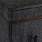Close-up of a dark wood cabinet corner with a distressed black finish, a horizontal bronze metal accent strip, and part of a dark metal handle visible.