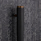 A close-up of a modern cylindrical door handle featuring a textured black leather wrap and a warm bronze metal top and side hardware, set against a dark charcoal wood-grain background.