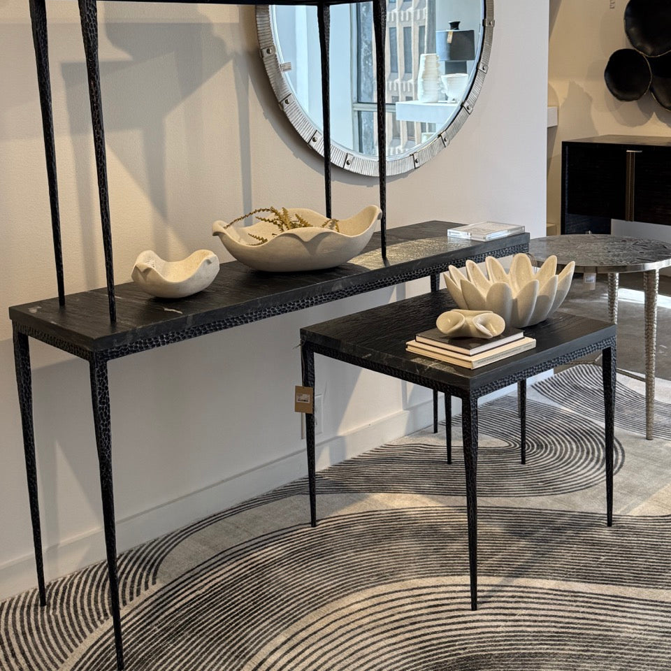 Console table with decorative items and a round mirror in a room setting.