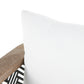 Close-up of a white pillow on a wooden chair with a black and white patterned rug.