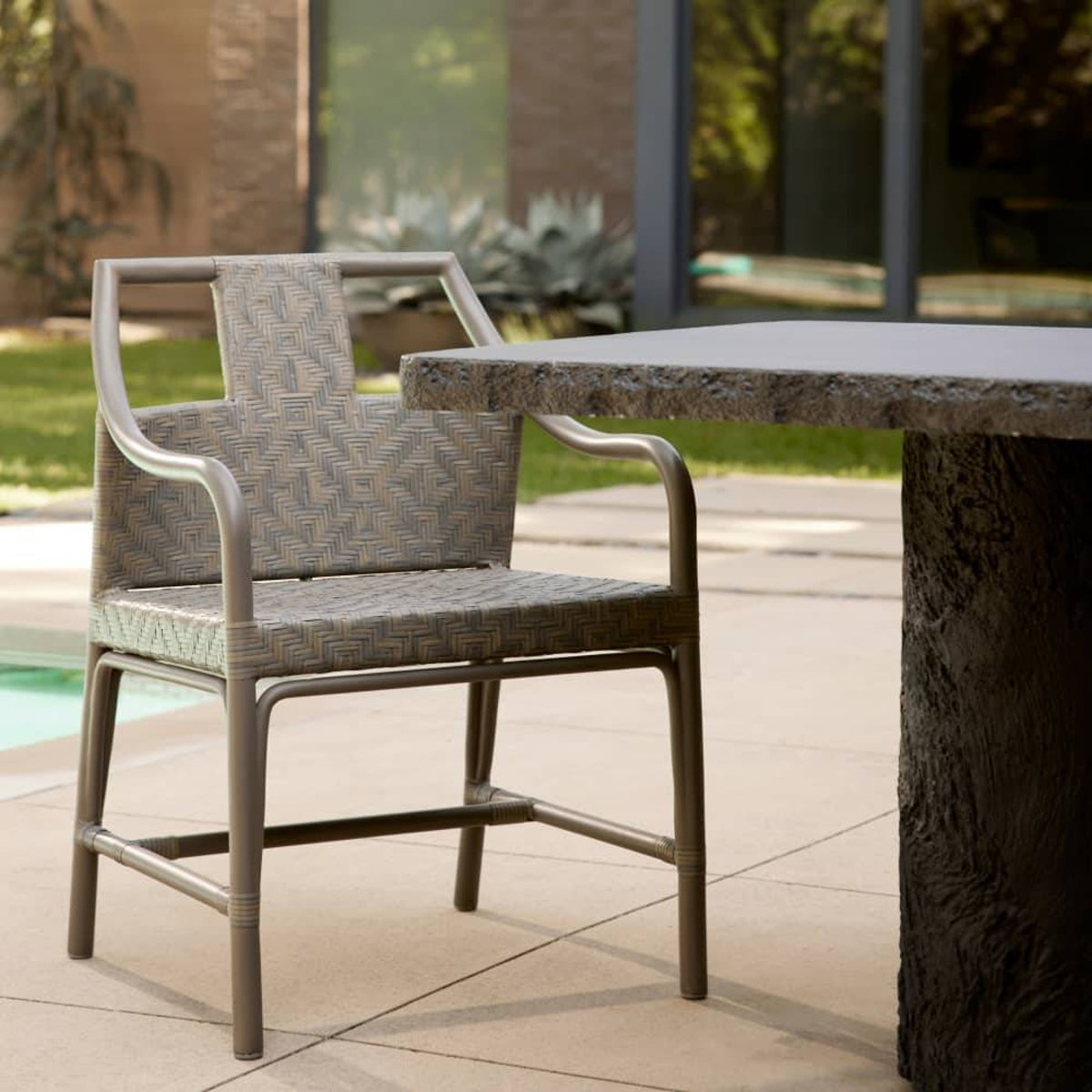 Outdoor chair with patterned cushion next to a stone table on a patio.