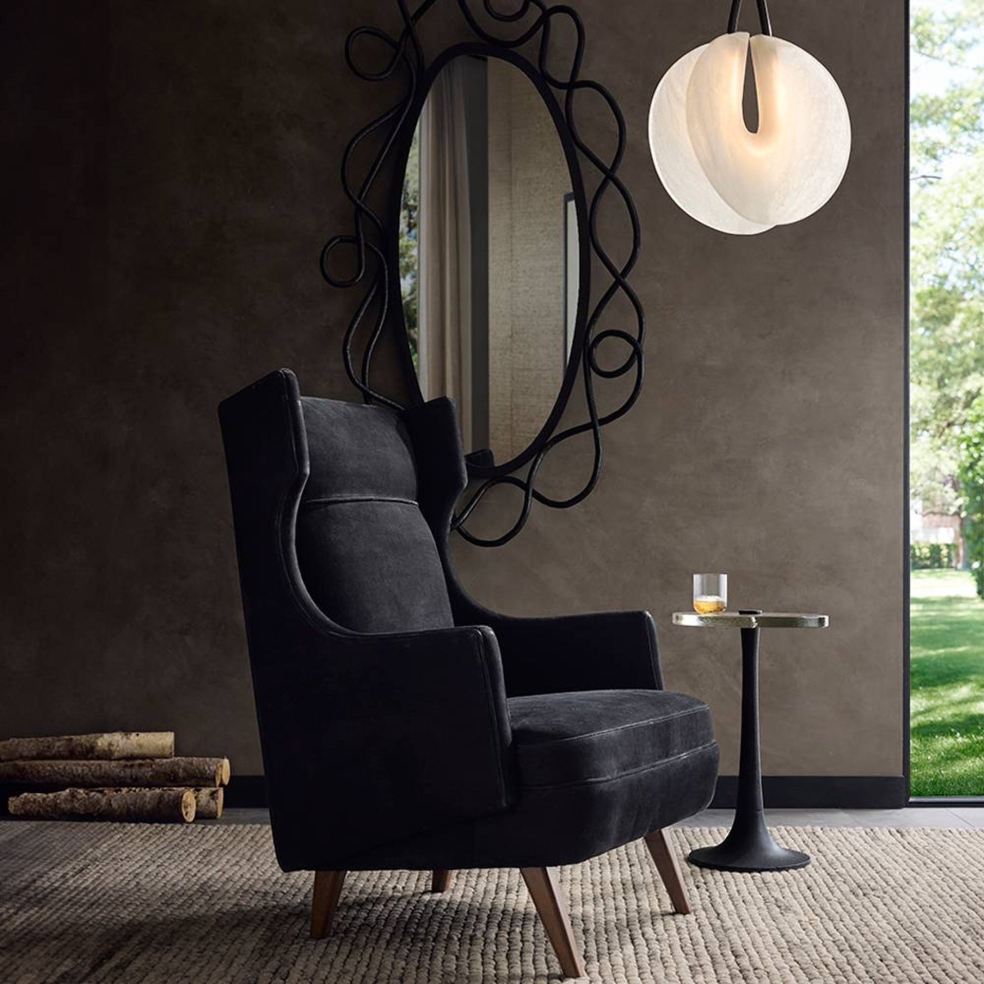 Modern interior with a dark gray armchair, decorative mirror, and small table.