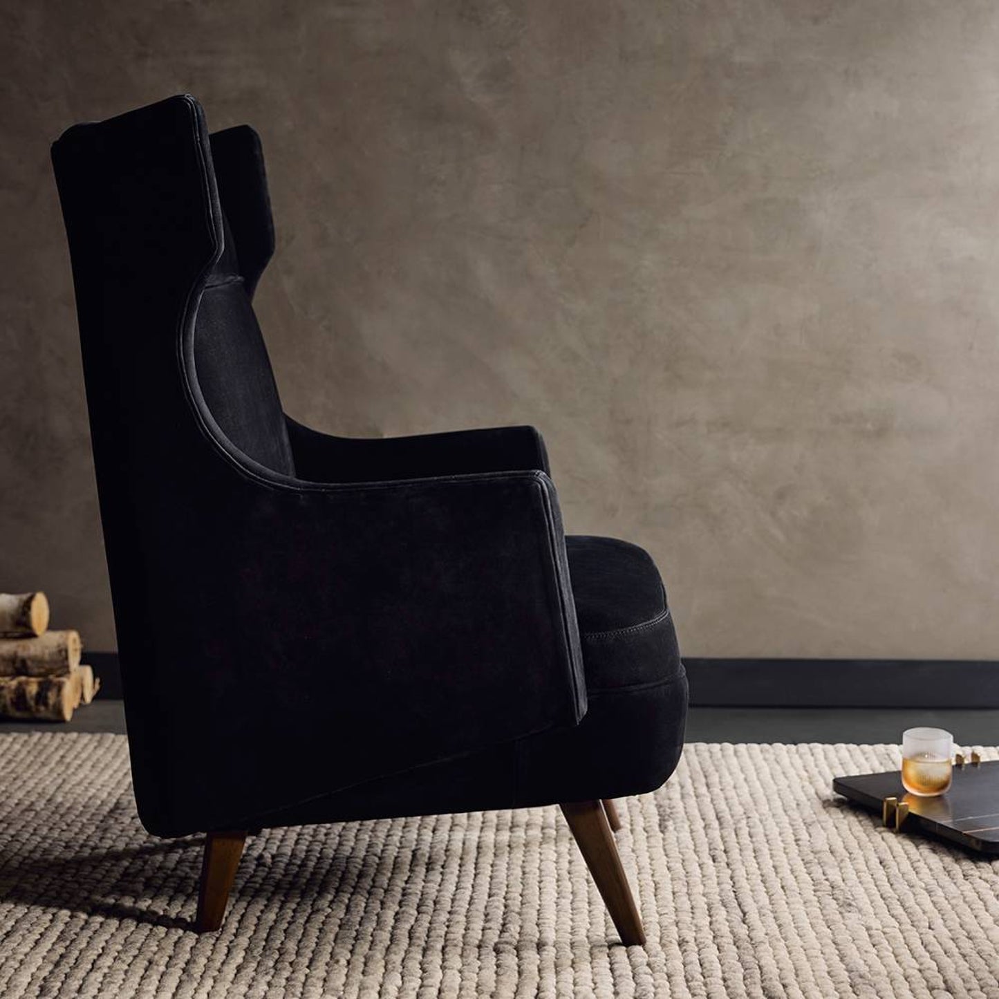 Black armchair in a room with a textured wall and rug.