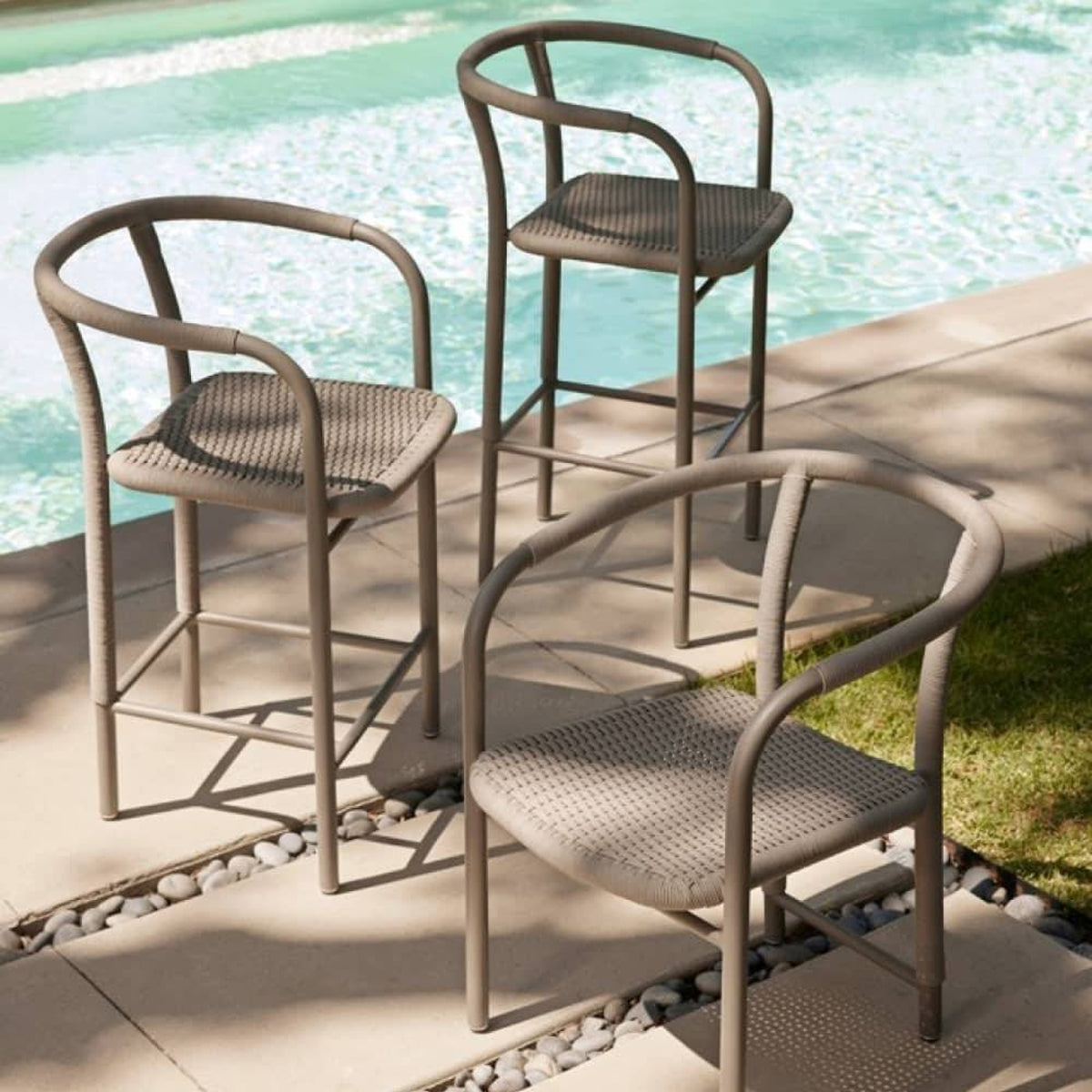 Three outdoor chairs by a poolside on a sunny day.