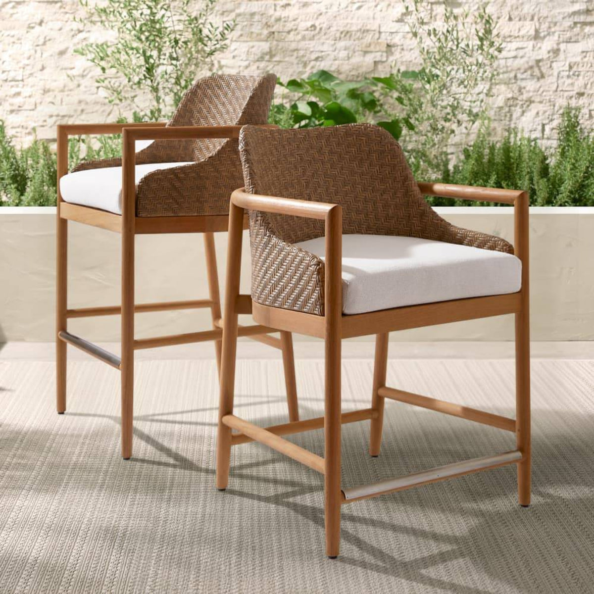 Two wicker chairs with white cushions on a patio