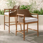 Two wicker chairs with white cushions on a patio