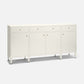 An off-white wooden sideboard cabinet with three drawers on top, two doors in the center, and three doors on the right, accented with small round gold knobs and supported by tapered legs, shown on a light gray background.