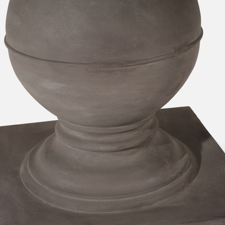 A close-up of a matte gray stone or concrete decorative urn base on a matching square pedestal, shown against a plain light background.
