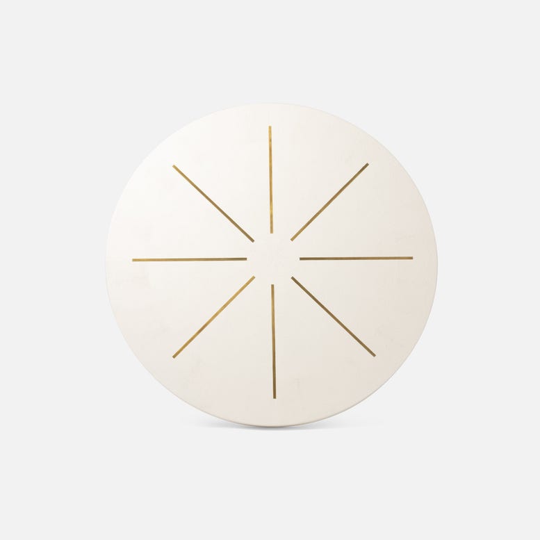 Round white object with gold starburst design on a light gray background