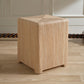 Wooden cube stool on a wooden floor with a neutral background