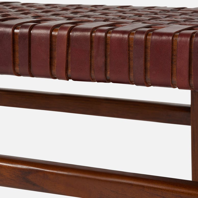 Close-up of a brown leather bench with woven pattern on a white background
