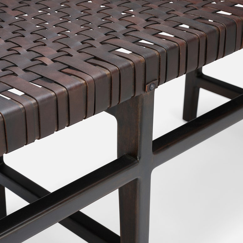 Close-up of a woven bench with metal frame on a white background