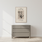 Gray dresser with a framed botanical print on a white wall.