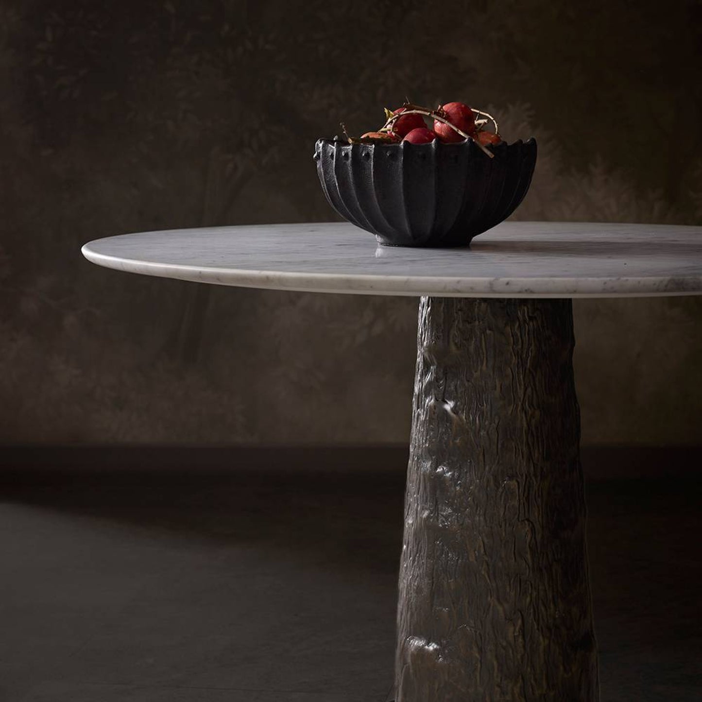 Marble table with a dark bowl containing red berries on a dark background