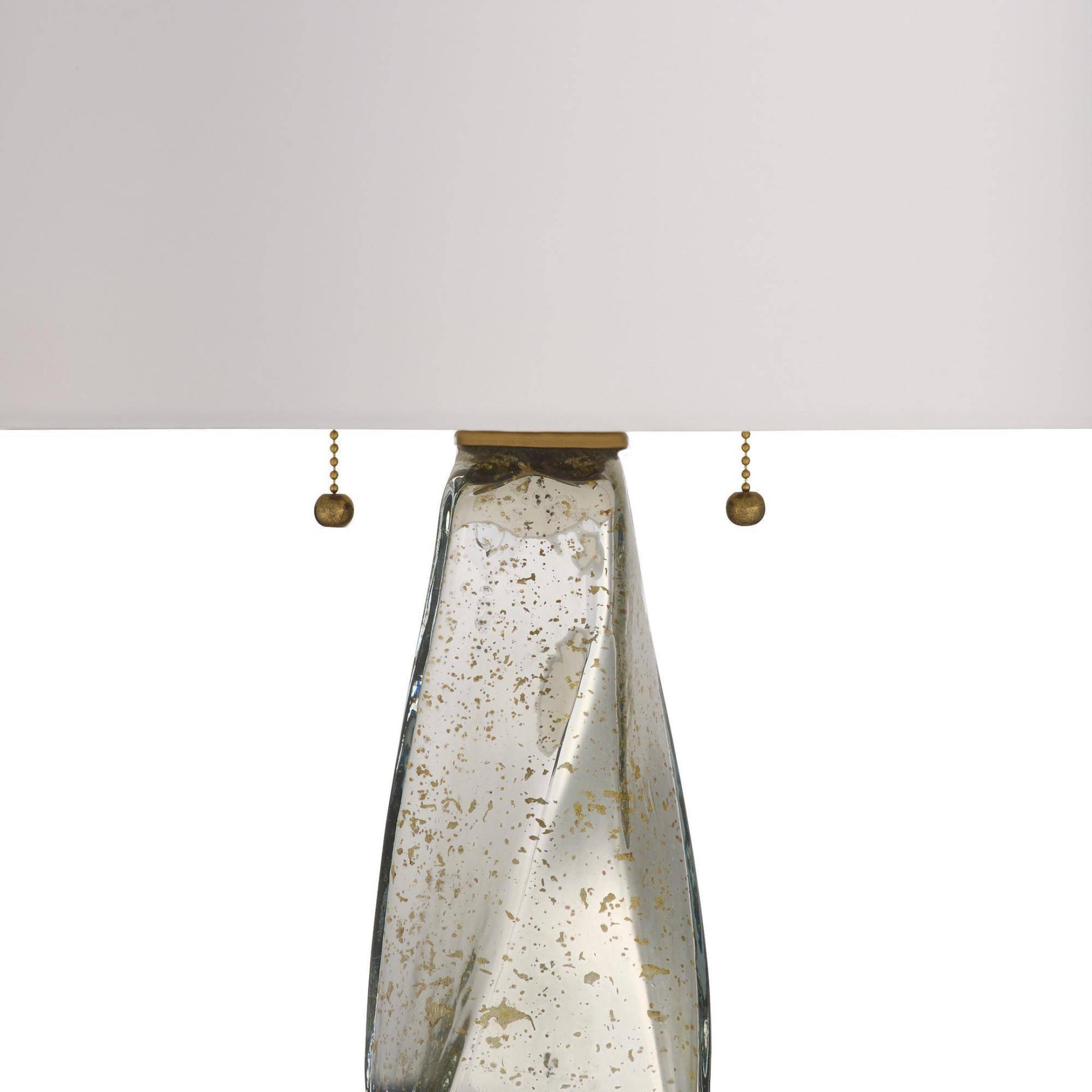 Close-up of a lamp with a textured glass shade and metallic pull chain on a white background