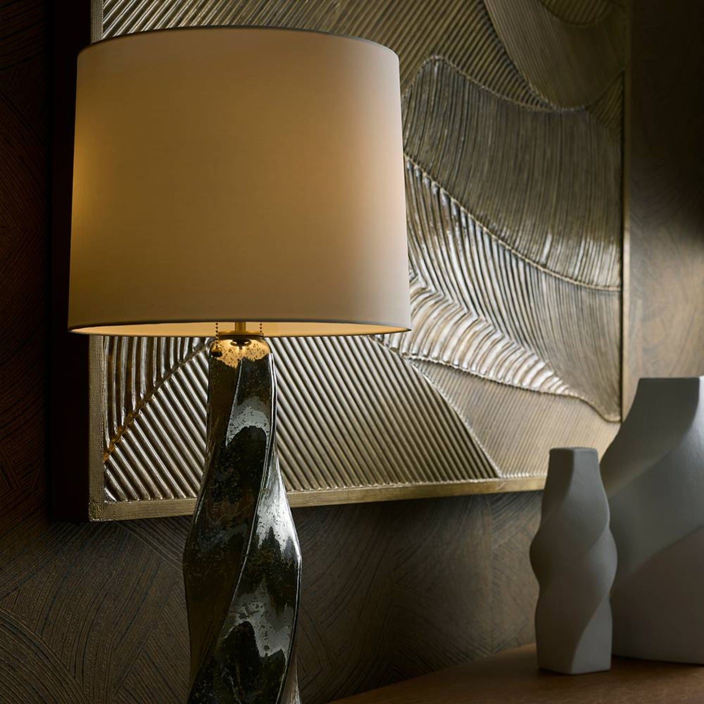 Decorative lamp with a textured base and leaf-patterned wall in the background