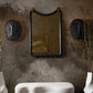 Decorative mirror with black frame on a textured wall with floral patterns