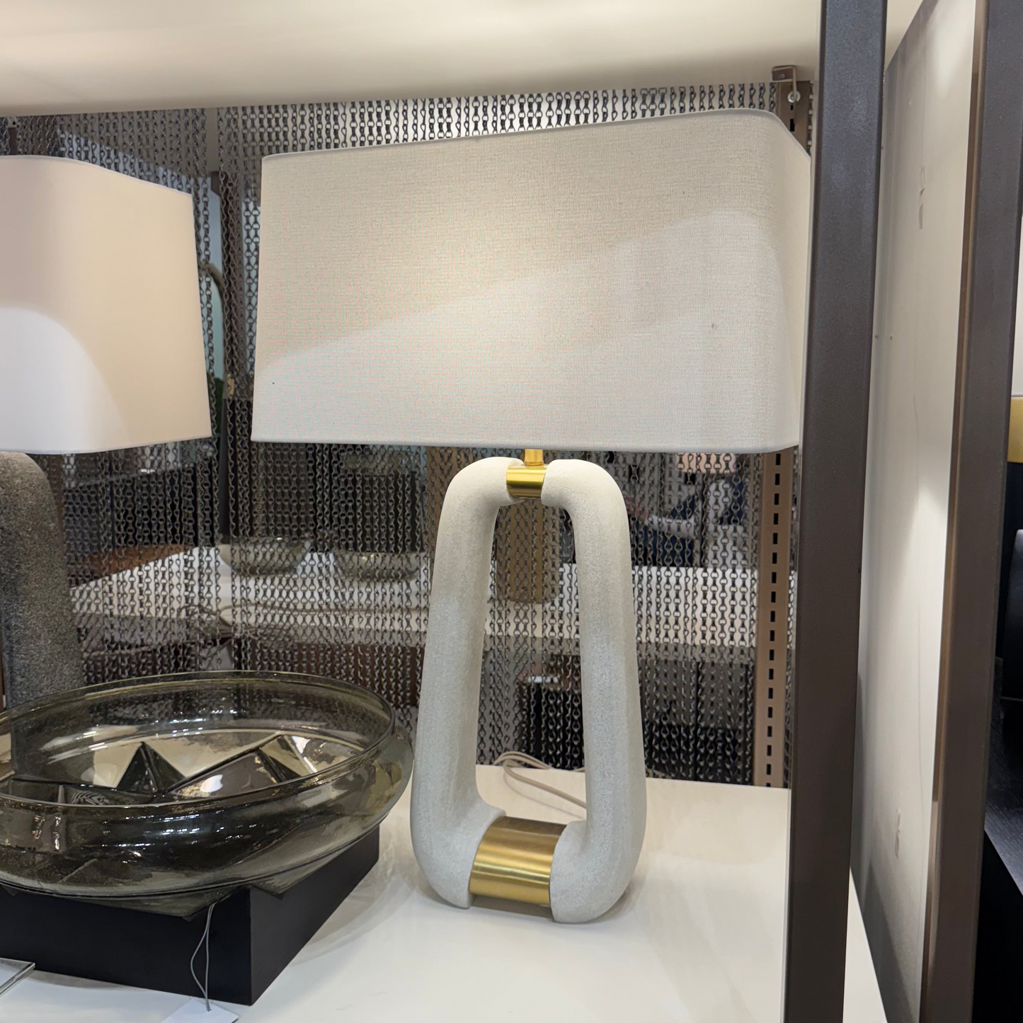 Two lamps on a display table with a reflective surface in the background
