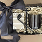 Black candle in a decorative box with a black ribbon on a beige background