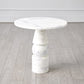 Marble dining table with stacked cylindrical legs on a wooden floor.