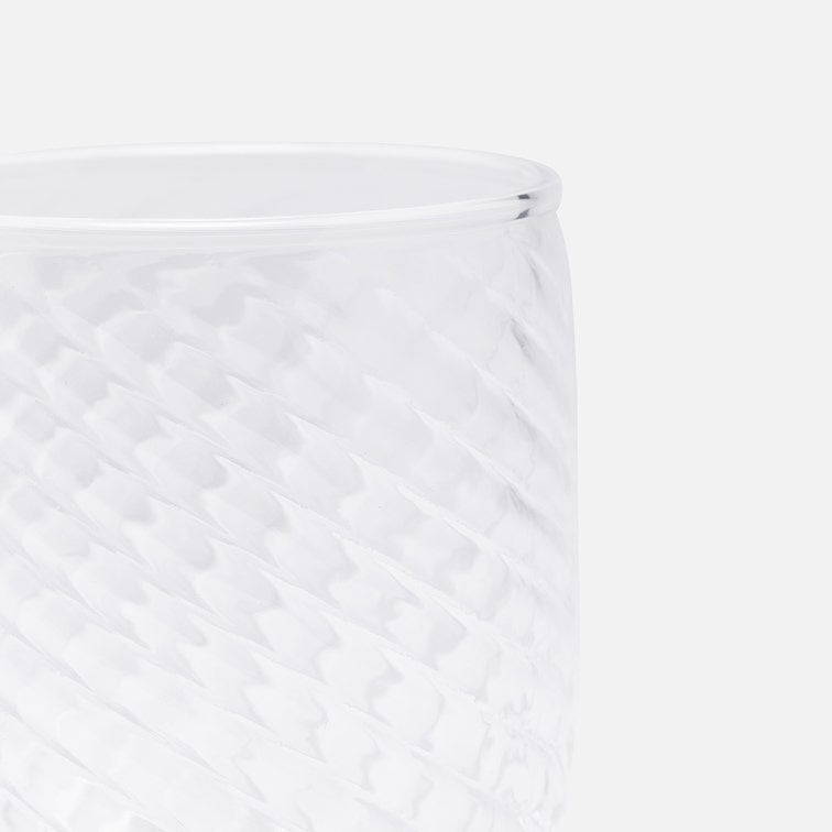 Close-up of a clear textured glass tumbler with a diamond-patterned surface, showing the rim against a plain white background.
